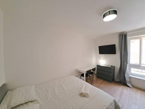 a bedroom with a bed and a desk and a television at Palerme - Appart'city in Reims