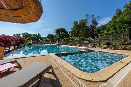 a large swimming pool with blue water in a resort at Vacances en Chalet ou Mobil-home chez Camp'in Pirellu in Porto-Vecchio