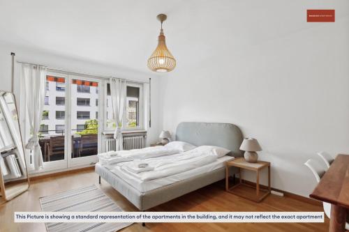 um quarto branco com uma cama e uma janela em 15-Min to Zurich Center: Cozy Apartment em Zürich