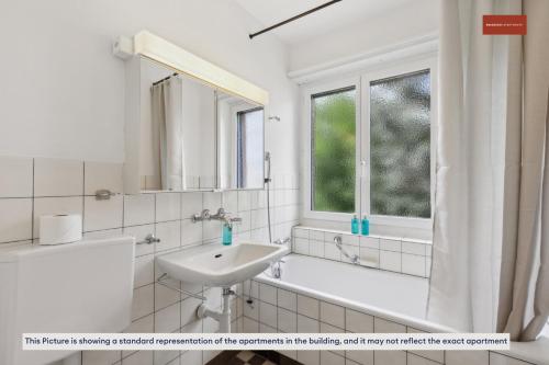 a white bathroom with a sink and a tub and a window at 15-Min to Zurich Center: Cozy Apartment in Zurich