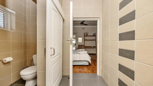 a small bathroom with a toilet and a bedroom at Anchor Bay Workation in Cape Town