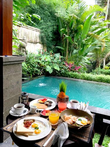 einen Tisch mit Essen neben einem Pool in der Unterkunft Poka Ubud Hidden Paradise & Spa by EPS in Ubud