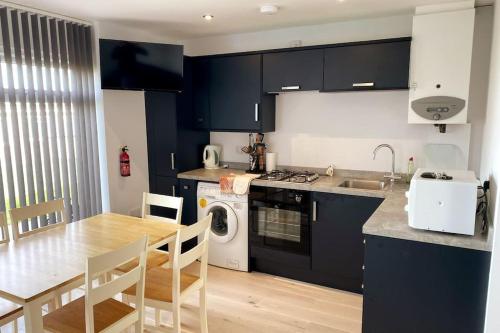 a kitchen with dark blue cabinets and a table and a sink at 107 Brambles Chine, Holiday Coastal Chalet in Freshwater