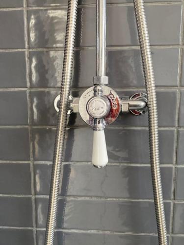a shower with a thermometer attached to a wall at 107 Brambles Chine, Holiday Coastal Chalet in Freshwater