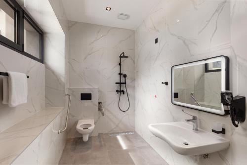 SeeSea Hotel في فوديس: حمام أبيض مع حوض ومرحاض