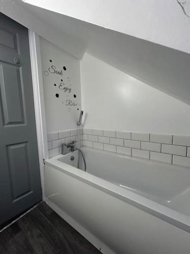 a bathroom with a bath tub and a sign on the wall at Rock Park Penthouse in Llandrindod Wells