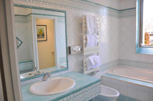 a bathroom with a sink and a tub and a mirror at Hôtel de France in Auch
