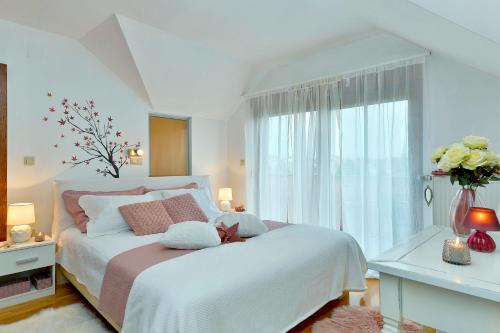 um quarto com uma cama branca e uma grande janela em 4 bedrooms villa with private pool jacuzzi and enclosed garden at Turcin em Črnec Biškupečki