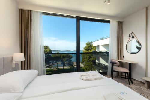 ein Schlafzimmer mit einem weißen Bett und einem großen Fenster in der Unterkunft SeeSea Hotel in Vodice