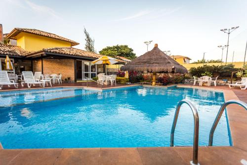 a swimming pool with chairs and a house at Pousada Pontal da Praia in São Pedro da Aldeia