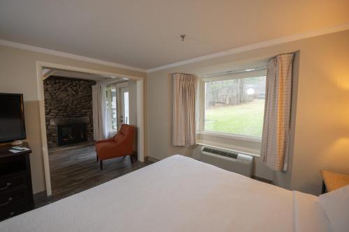a bedroom with a bed and a window and a chair at Peek'n Peak Resort Trademark Collection by Wyndham in Clymer