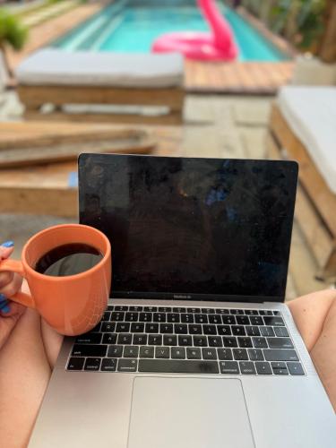a person holding a cup of coffee and a laptop at Wander Boutique Hotel in El Paredón Buena Vista