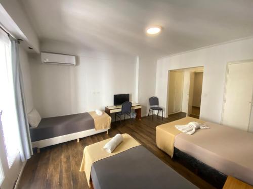 a hotel room with two beds and a desk at Hotel Chacabuco in Buenos Aires