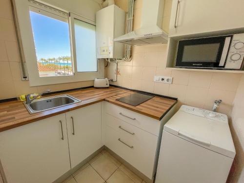 a small kitchen with a sink and a microwave at Sol y Mar Segur in Segur de Calafell