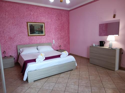 a bedroom with a bed and a pink wall at Casa Mandorle in Ugento