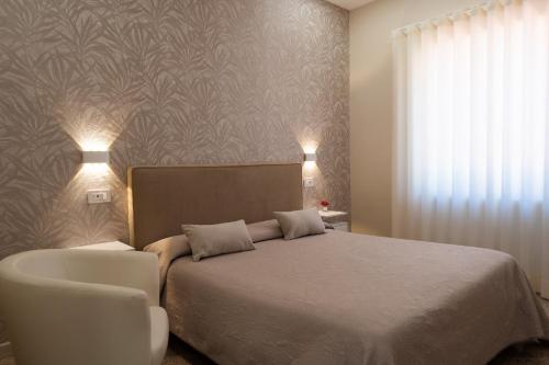 een slaapkamer met een bed en een witte stoel bij Leonardo'S in Agerola