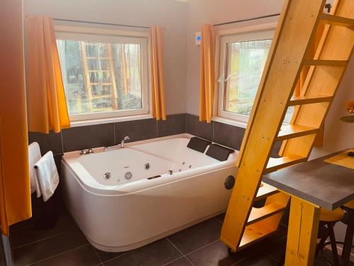 baño con bañera blanca grande y 2 ventanas en Privátní wellness domek RockStar en Smržovka