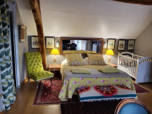 a bedroom with a large bed and a green chair at Les Glycines in Ury