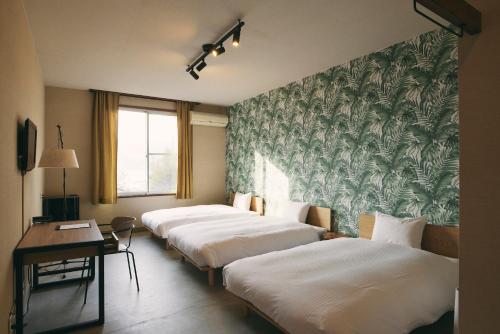 uma fila de camas num quarto de hotel em Hanaguri-しまなみ海道スマート旅館 em Ikata