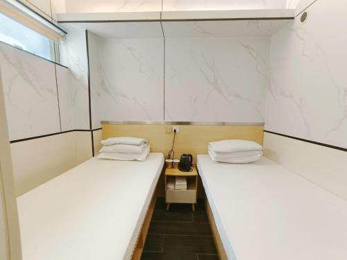 two beds in a small room with white walls at L'etoile Hella Inn in Hong Kong
