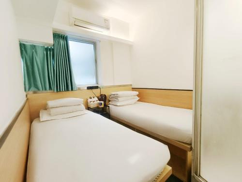two beds in a room with a mirror at L'etoile Hella Inn in Hong Kong