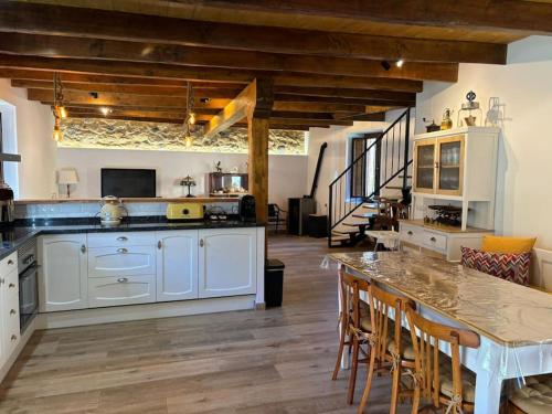 una cocina con armarios blancos y una mesa con sillas. en La Casa de la Abuela Concha, 