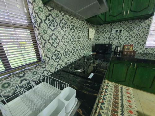 a kitchen with a stove and a counter with white chairs at Teratak D Tuntung in Kampong Mesjid