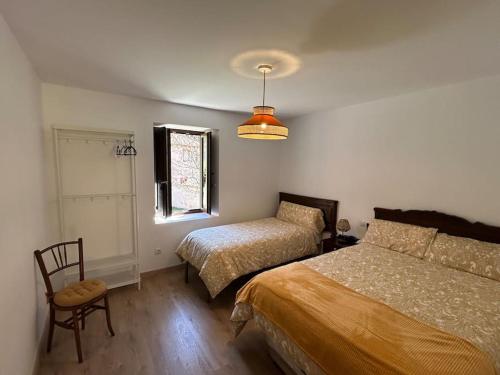 a bedroom with two beds and a chair and a window at La Casa de la Abuela Concha in Felmín