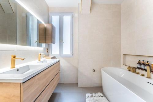 een witte badkamer met een bad en een wastafel bij Appartement cosy à 5min de Paris in Saint-Mandé