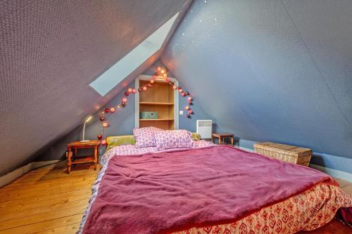 um quarto com uma cama roxa num sótão em Gîte calme avec jardin et terrasse 