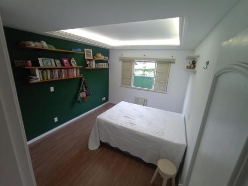 a bedroom with a white bed and a green wall at Cantinho do Sossego in Rio de Janeiro