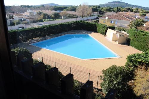 une grande piscine bleue dans une cour dans l'établissement Studio Calista - Quartier Naturiste Cap d'Agde, au Cap d'Agde