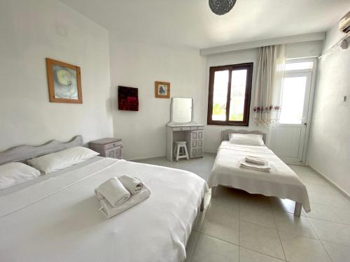 um quarto branco com 2 camas e uma janela em Akdeniz Pansiyon em Ekincik