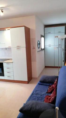 een woonkamer met een blauwe bank en een keuken bij Valledoria in Valledoria