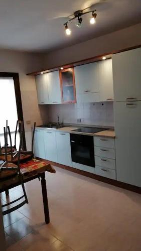 een keuken met witte kasten en een tafel en een stoel bij Valledoria in Valledoria