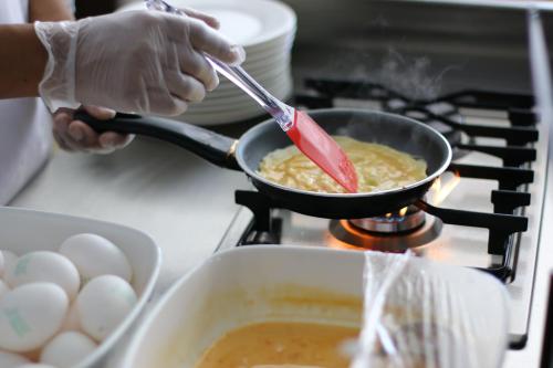a person cooking food in a pan on a stove at Premier Hotel in Manama