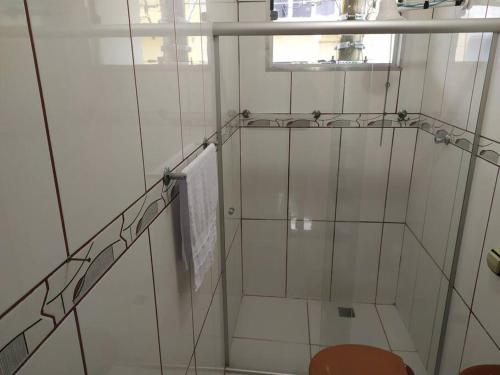 a glass shower in a white room with a window at Casa próximo ao santuário nacional in Aparecida