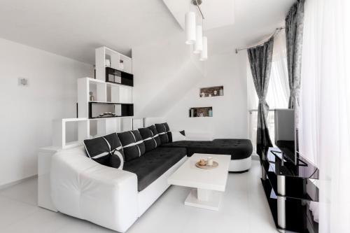 a white living room with a couch and a tv at NEA Penthouse in Ahtopol