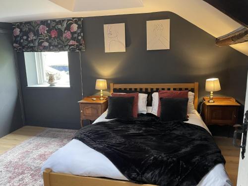 a bedroom with a bed with a black blanket on it at Stunning 2-bedroomed Cottage in Cockermouth