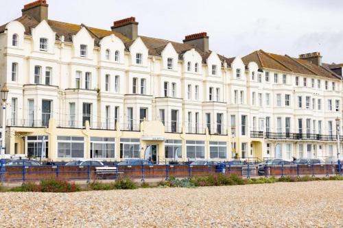 un grand bâtiment blanc avec des voitures garées devant lui dans l'établissement The Majestic Hotel, à Eastbourne