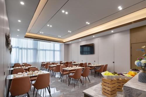 a dining room with tables and chairs and a screen at Shenzhen Zhongchen International Hotel - Shenzhen Baolong Subway Station Branch in Shenzhen