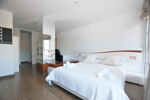 um quarto com uma cama branca e um espelho em Rey apartment em Vilassar de Mar