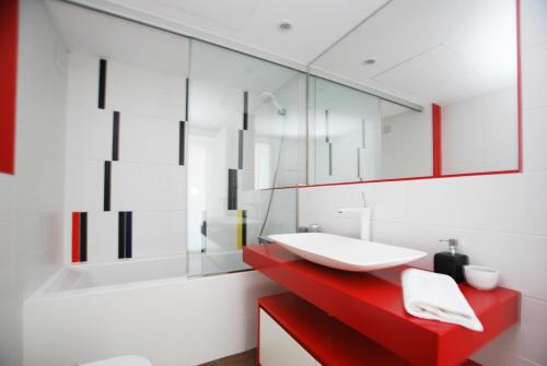 uma casa de banho com um lavatório vermelho e um espelho. em Rey apartment em Vilassar de Mar
