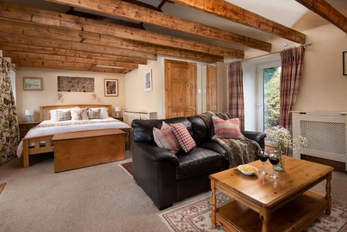 a living room with a leather couch and a bed at The Bothy, Press Mains Farm Cottages in Eyemouth