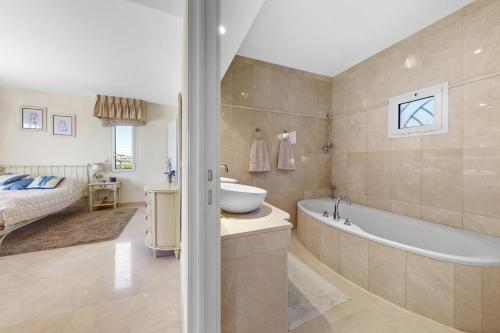 une salle de bain avec une baignoire et un lavabo et un lit dans l'établissement Superbe appartement 3 chambres avec vue panoramique, à Mandelieu-la-Napoule