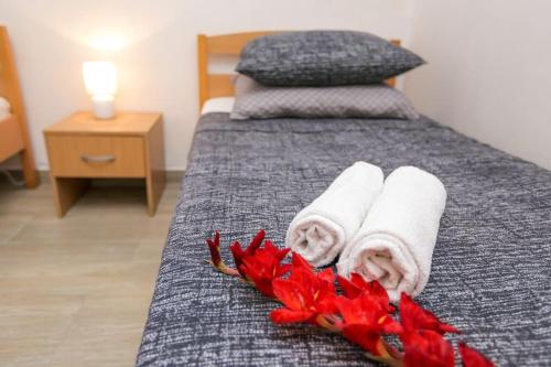 ein Hotelzimmer mit Handtüchern und roten Blumen auf dem Bett in der Unterkunft Apartments Petar in Rtina