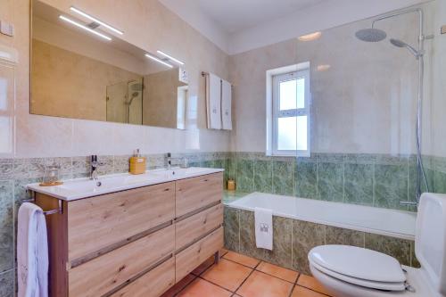 a bathroom with a toilet and a tub and a sink at Villa Oliveiras de Vilamoura by The Portuguese Butler in Quarteira