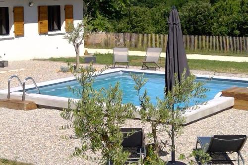 een klein zwembad met een parasol en stoelen bij Maison climatisée avec piscine privée, 6 personnes in Aiguèze