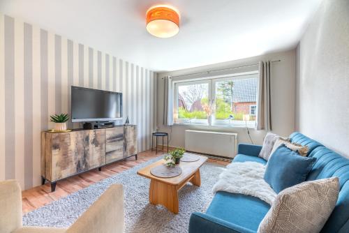 uma sala de estar com um sofá azul e uma televisão em Annis Huus NEU em Wyk auf Föhr