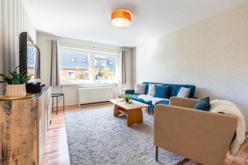 uma sala de estar com um sofá azul e uma janela em Annis Huus NEU em Wyk auf Föhr
